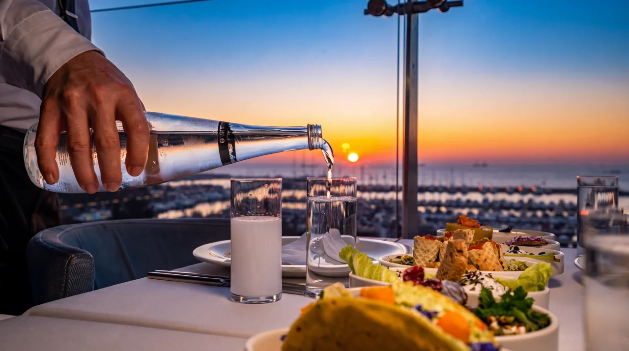 Gün batımı penceresi yanında yemek sunan restoran görevlisi