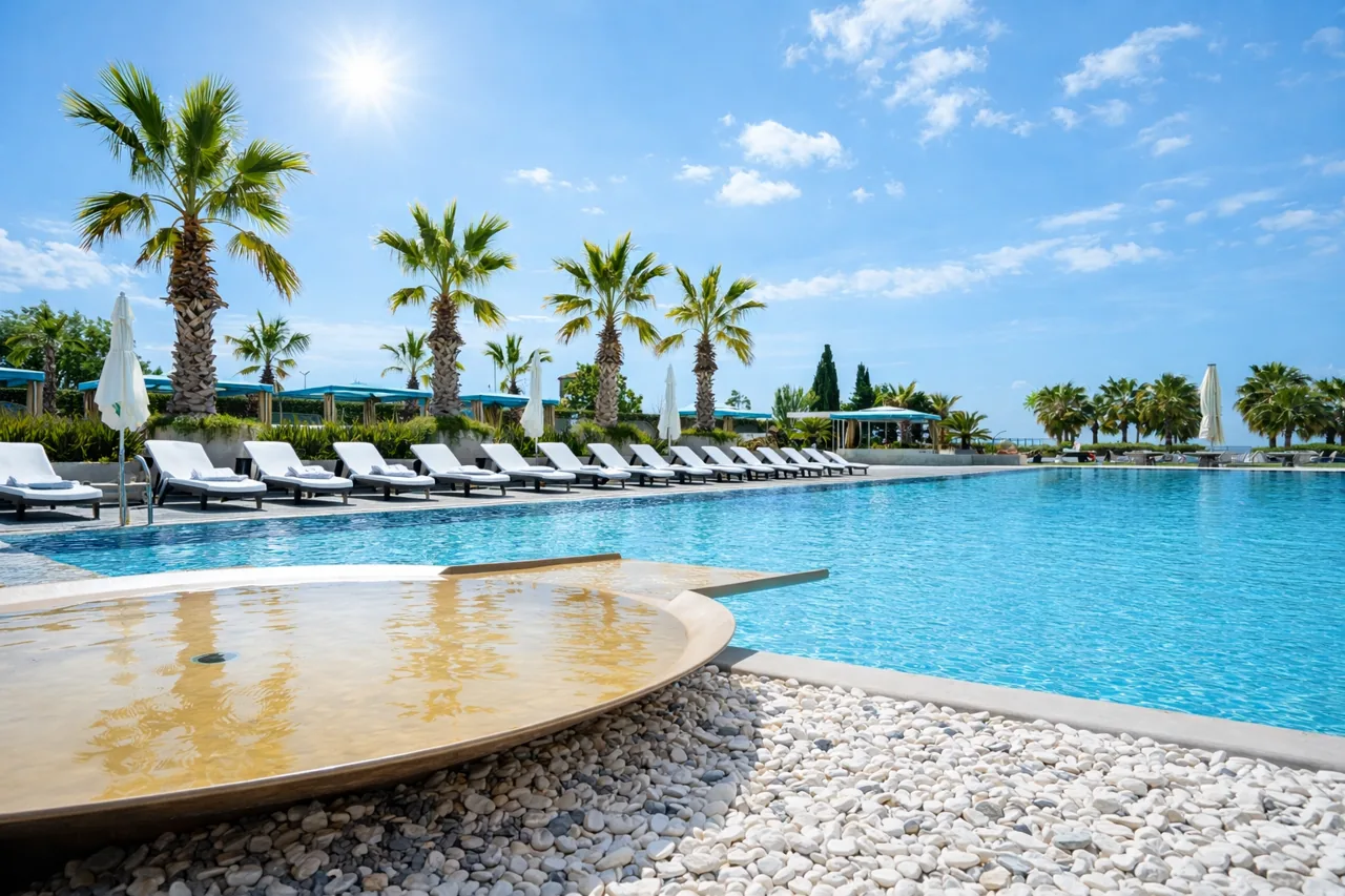 Mavi gökyüzü altında palmiye sıralı resort yüzme havuzu